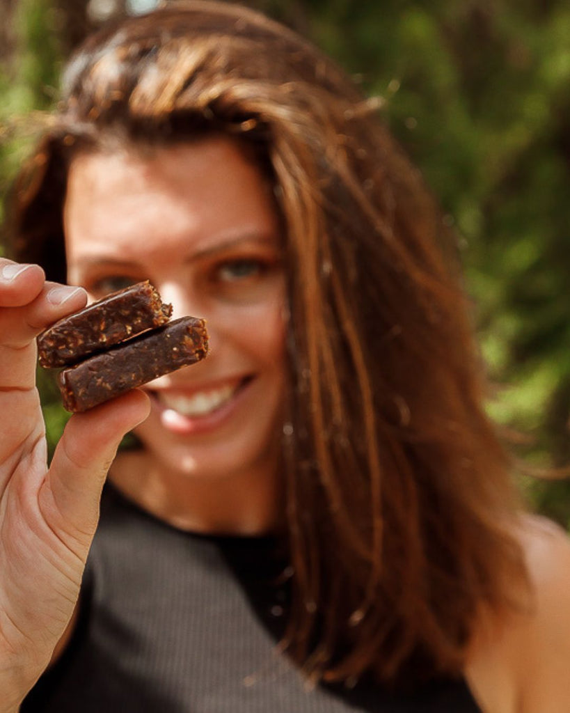 Energy bar in hand van blije sportvrouw